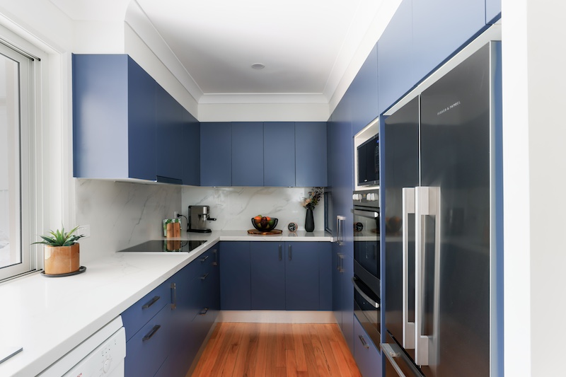 Explore this stunning modern kitchen renovation by Dura Group, a leading family-owned building company based in Sydney. Our expertise in kitchen upgrades is evident in this beautifully designed space, featuring sleek blue cabinetry, high-quality stainless steel appliances, and a sophisticated marble backsplash. The elegant wooden flooring adds warmth and style, creating a perfect balance of function and aesthetics. At Dura Group, we prioritize time efficiency, budget-conscious planning, and consistent communication to ensure a seamless renovation experience. This kitchen transformation embodies our commitment to delivering exceptional build quality without compromise. Operating across regions including Sutherland Shire, Bayside, Inner West, Georges River, and Randwick, we pride ourselves on a homeowner-first approach, focusing on trust, transparency, and tailored solutions. Whether you're considering a kitchen remodel or any home renovation, our team of experts is ready to bring your vision to life. Elevate your home with Dura Group today and transform your living spaces into something extraordinary. Contact us to start your renovation journey now!