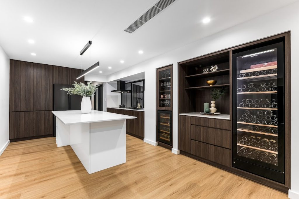 Contemporary kitchen with island, wine storage, and wood accents by Dura Group.