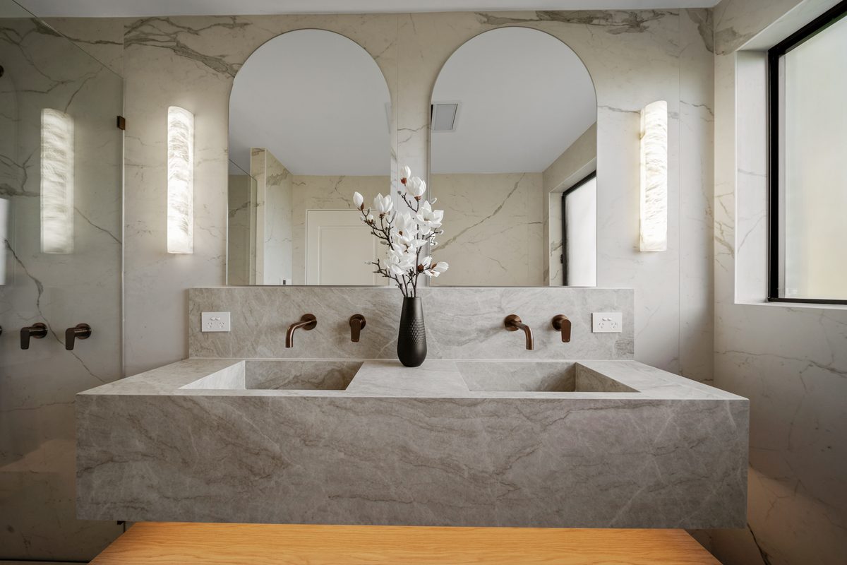 Ensuite renovation with stone double vanity and arched mirrors