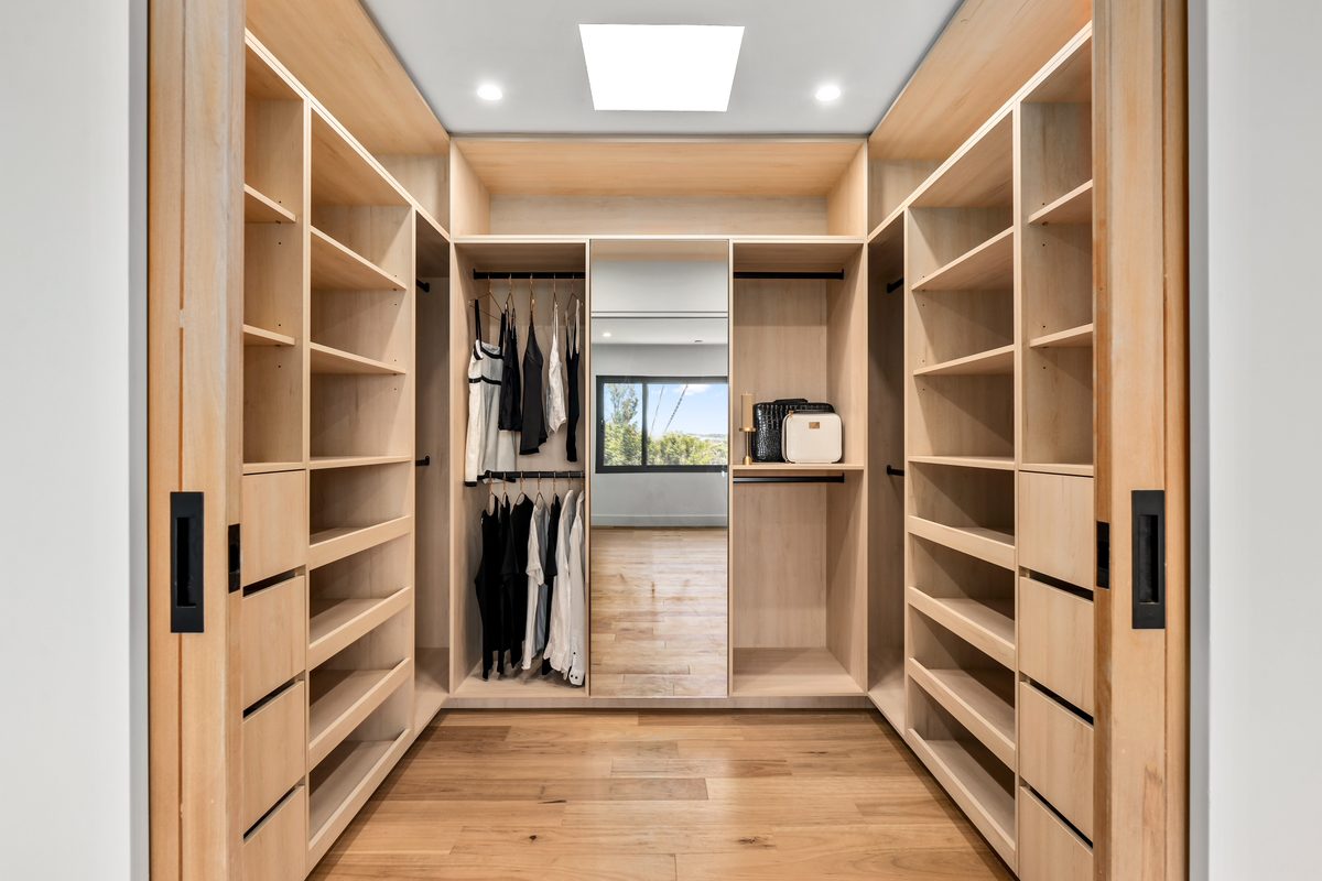 Walk-in wardrobe with custom timber joinery and skylight